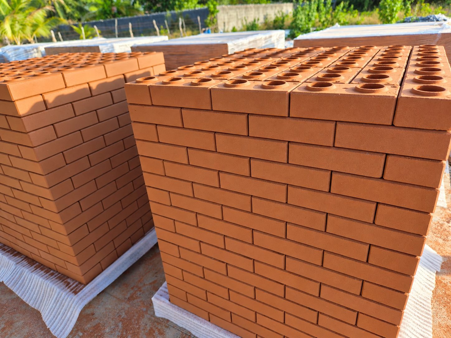 Paletes de tijolos ecológicos ARVONI na cor terracota, com furos de encaixe aparentes